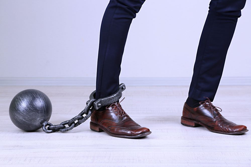 Business worker with ball and chain attached to foot