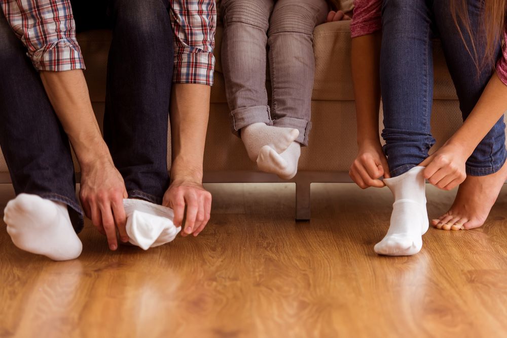 Young family of three putting on socks over a polished wooden floor.jpg