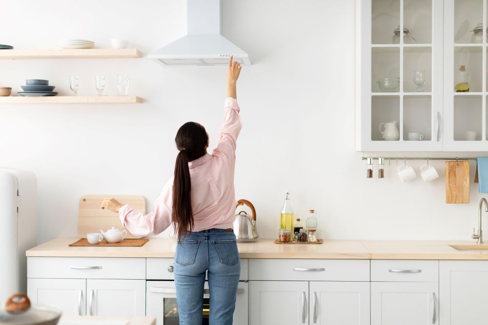 Woman select mode on cooking hood in kitchen
