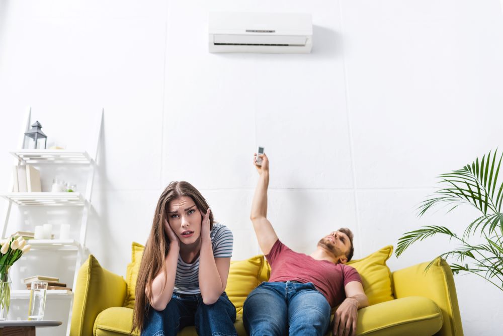 Exhausted couple sitting home with broken air conditioner