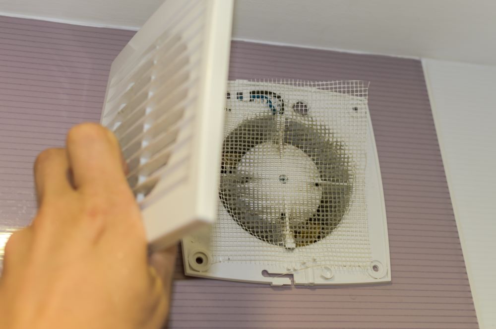 Hand disassembles a wall-mounted house fan