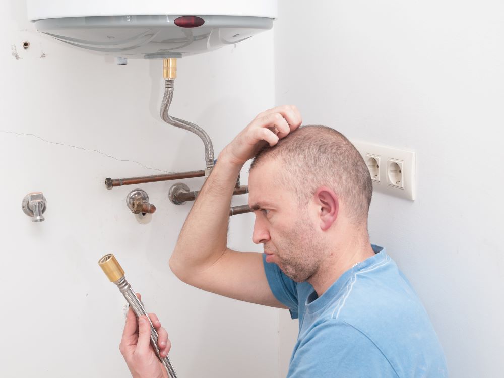 Inexperienced plumber holding a water heater element; anode rod