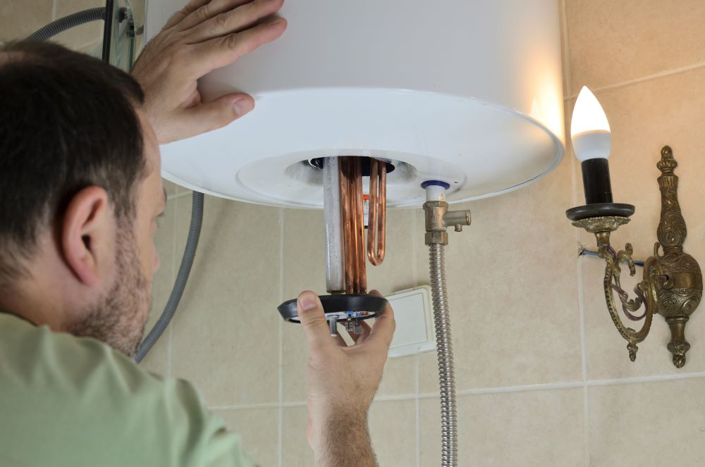 man removing water heating element from a tank water heater