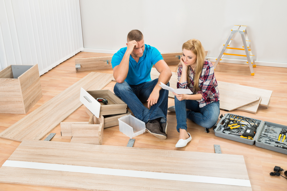 Portrait Of Contemplated Couple With Disassembled Furniture Parts In New Home