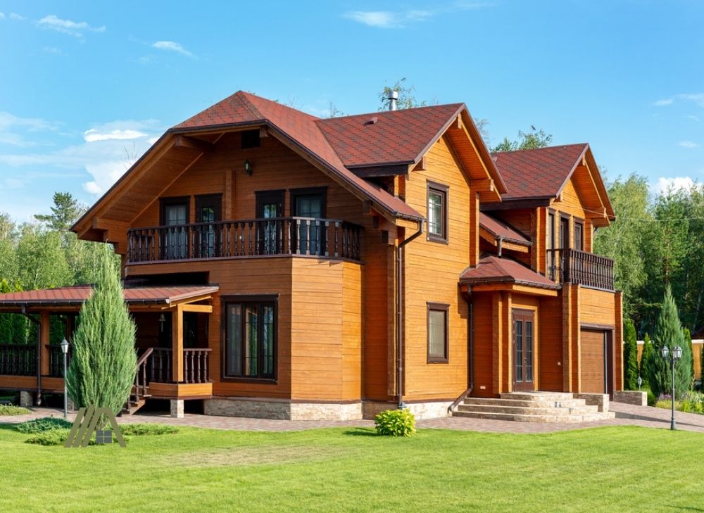 Beautiful luxury big wooden house. Timber cottage villa with with green lawn, garden and blue sky on background.