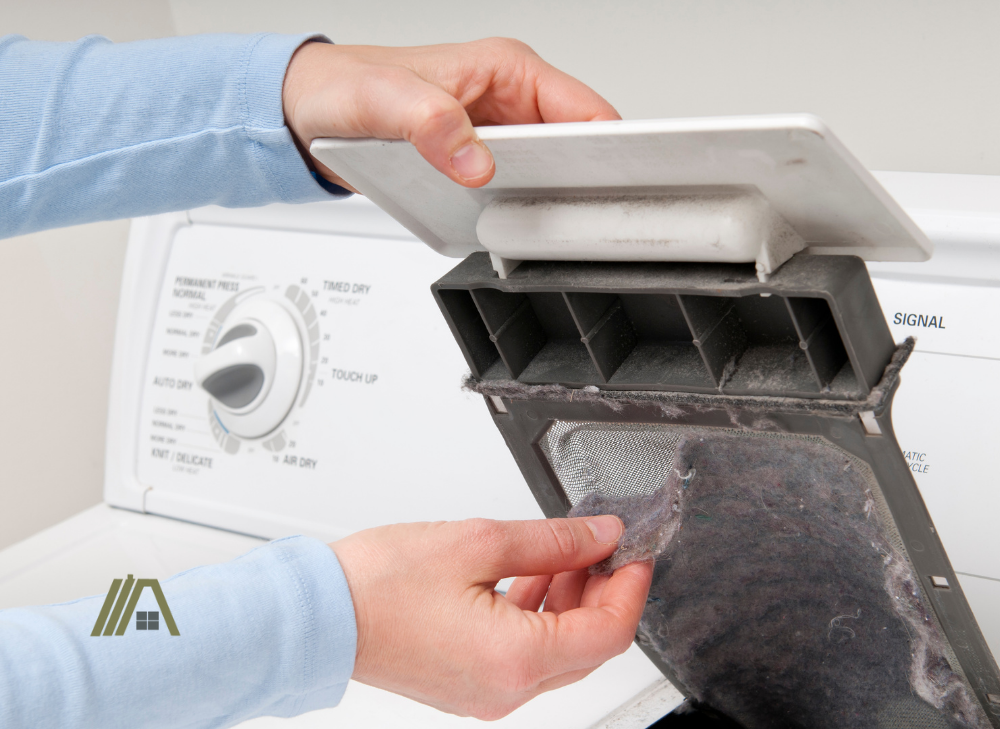 hands cleaning and removing the lint from uncleaned dryer's lint trap