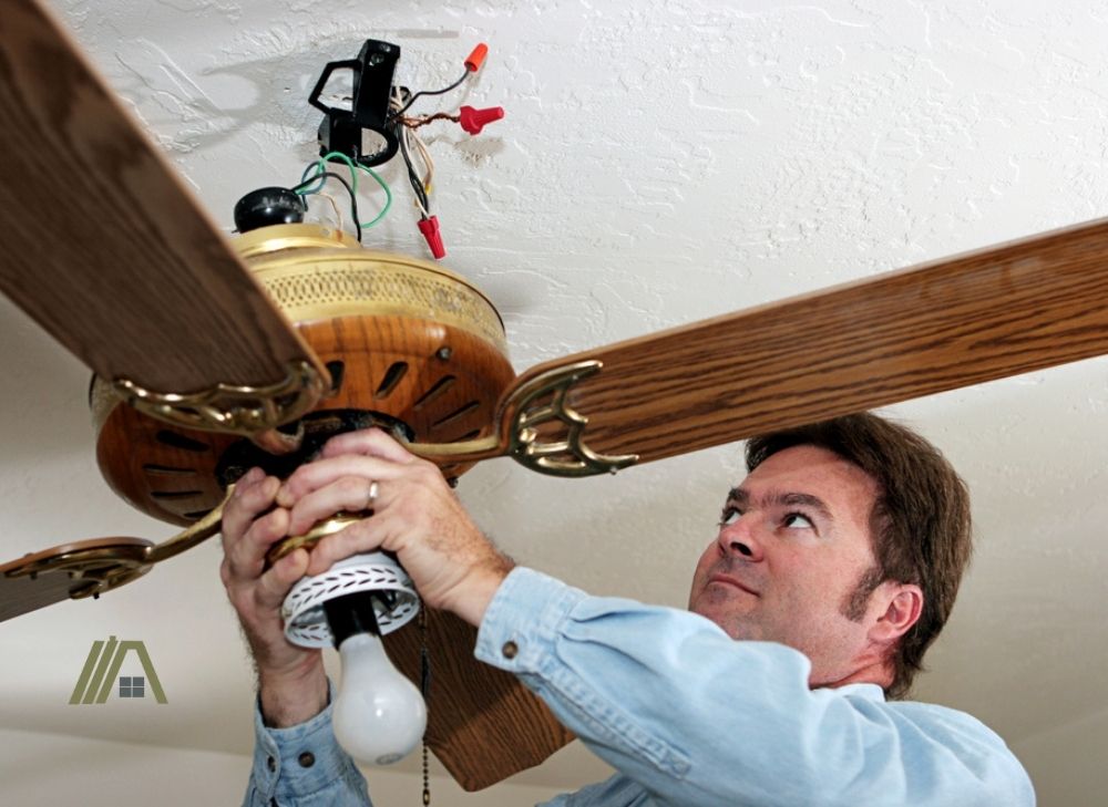 man checking the wiring of a ceiling fan