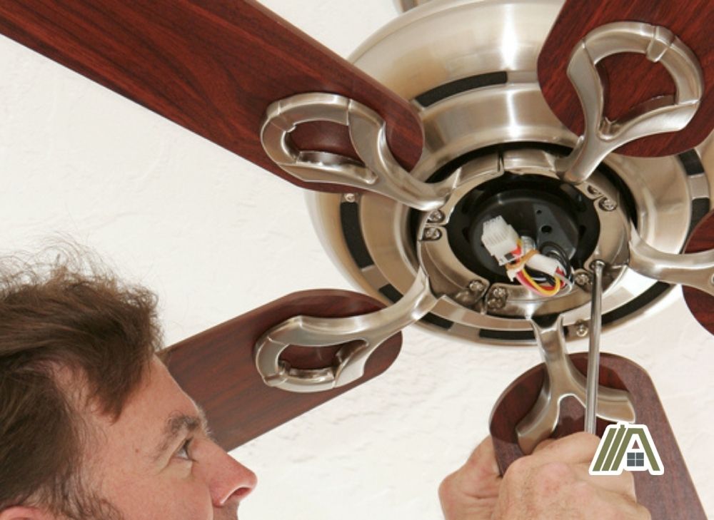 man unscrewing the ceiling fan