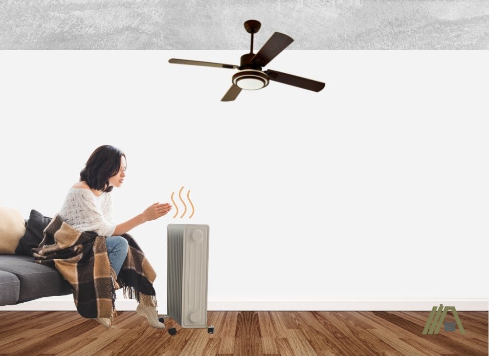 woman heating frozen hands to the space heater with ceiling fan on top