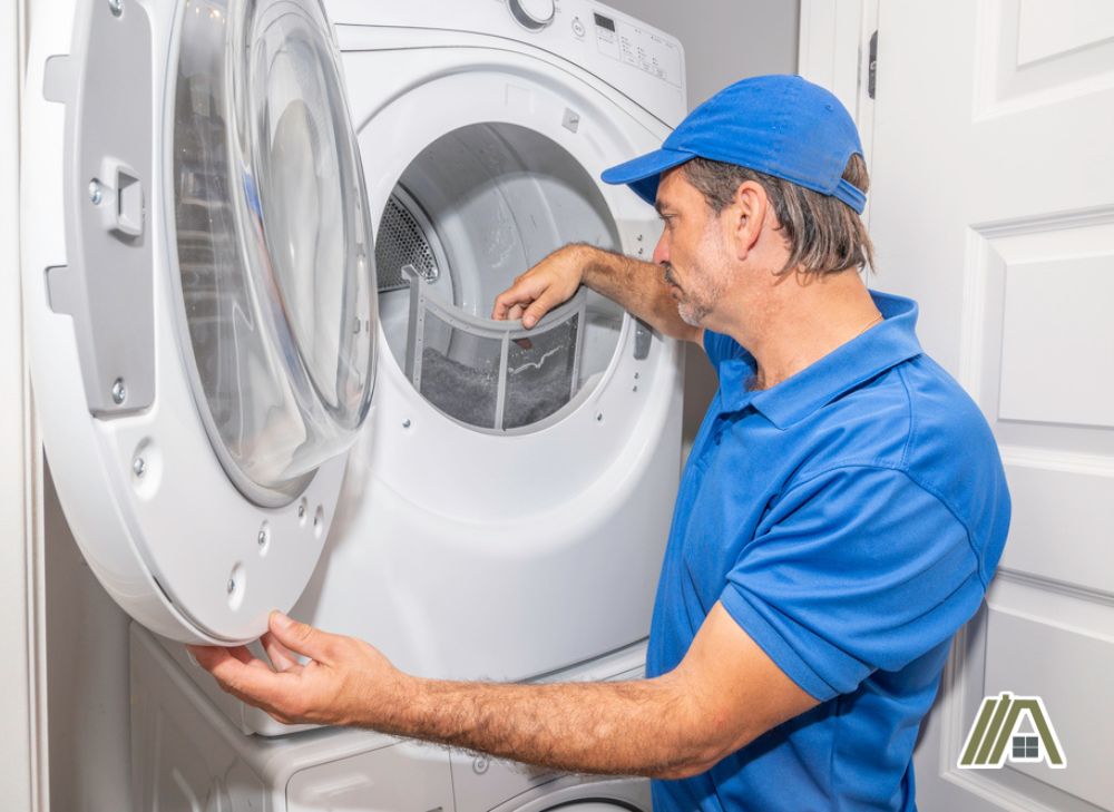 Man wearing a blue cap and a blue shirt removing the lint filter of a white dryer