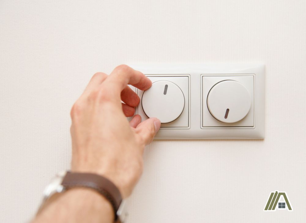 Man wearing a watch turning the dimmer switch