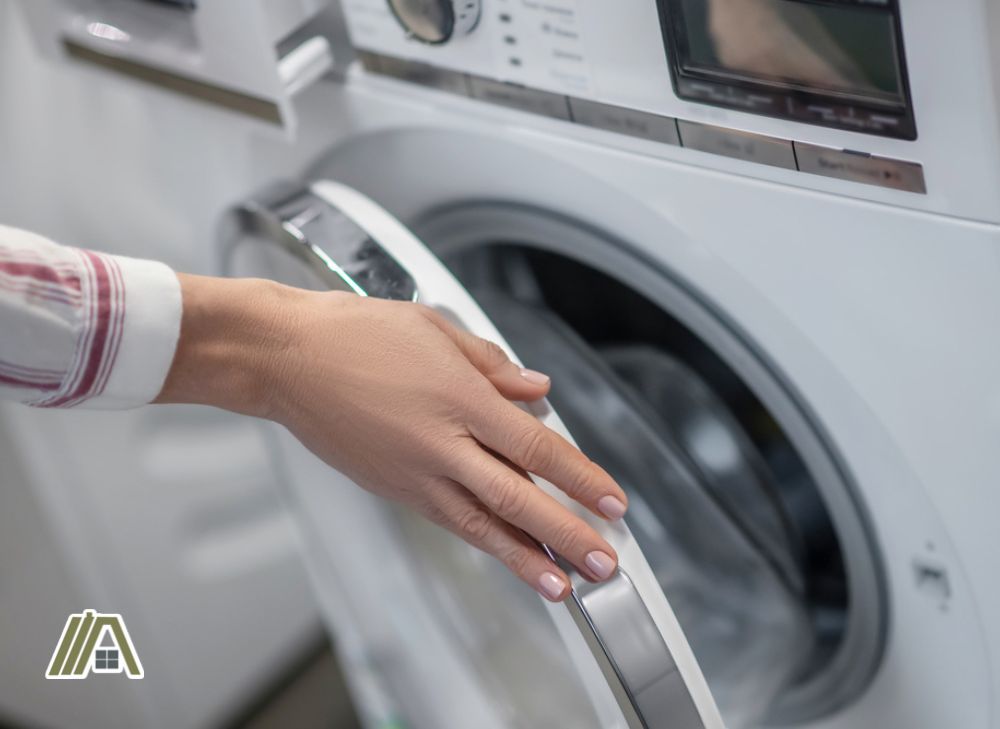 Woman's hand opening the door of a washer