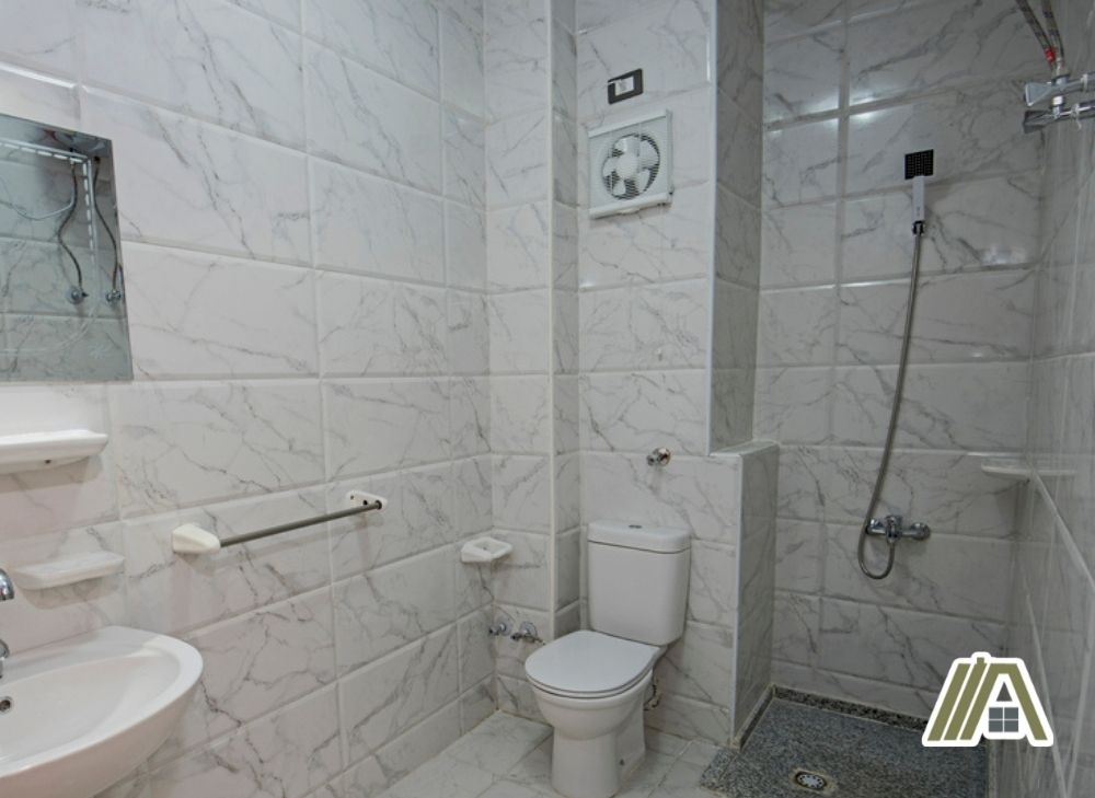 Bathroom exhaust installed in a wall full of white tiles