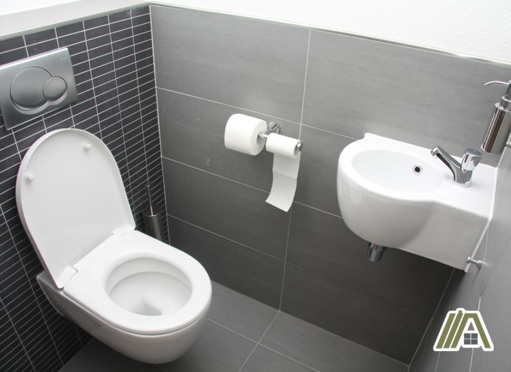 White toilet and sink with gray and black tiles on walls