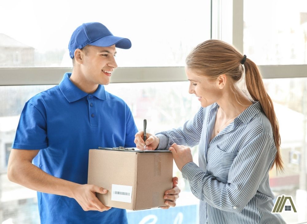 Delivery man holding a package and a blonde woman signing the receiving form