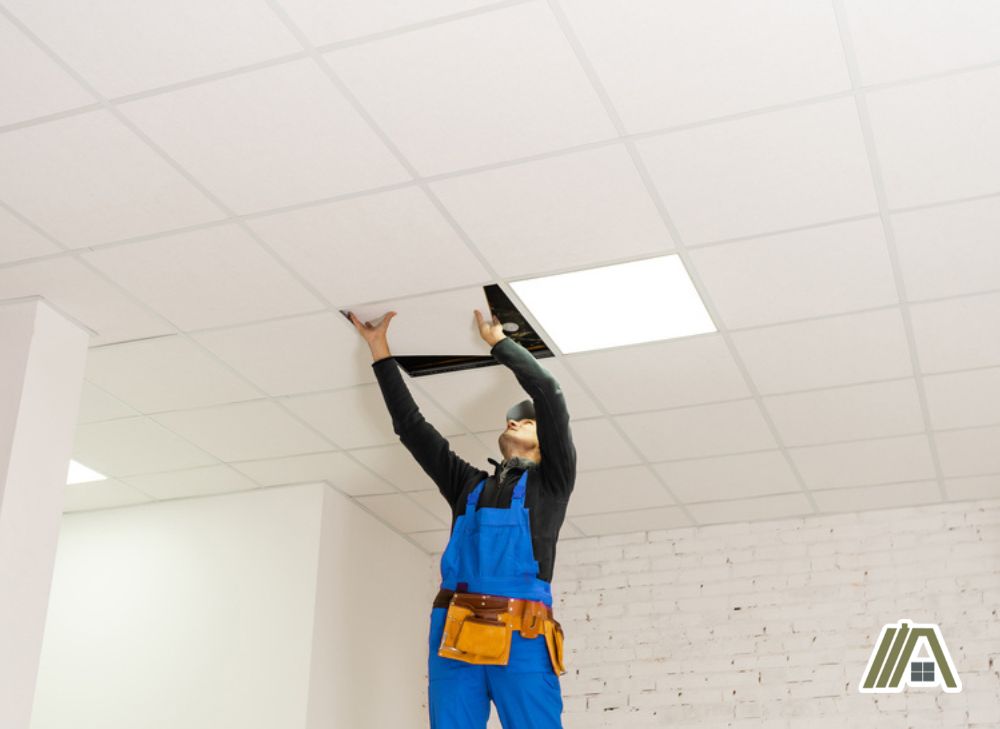 Handyman installing white drop ceiling tiles
