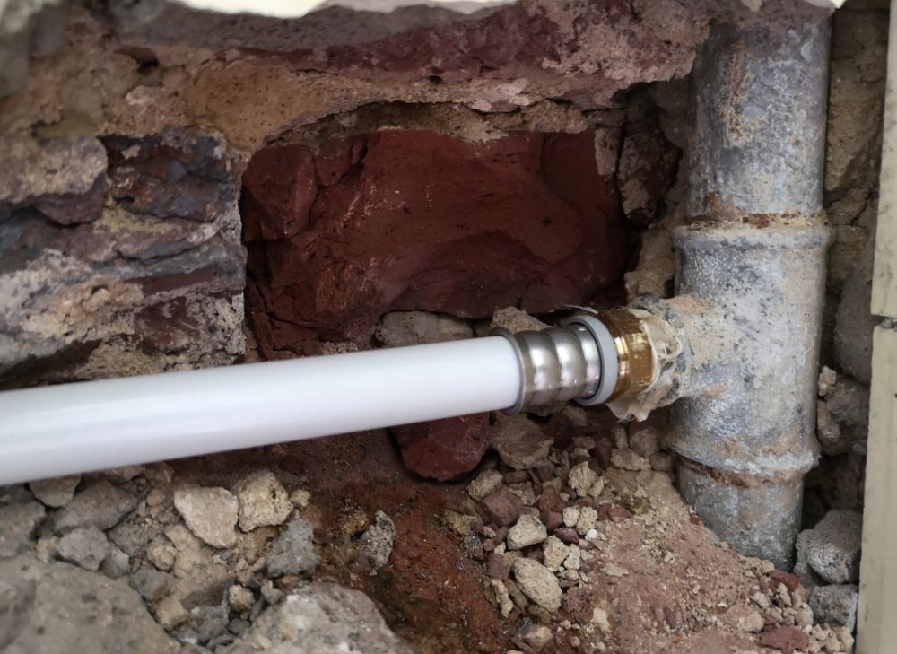 Old pipe and new white pipe installed in concrete wall