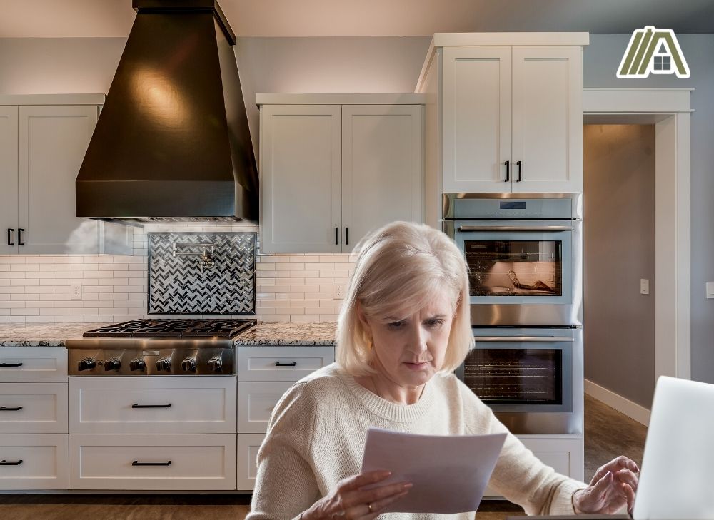 Old woman checking her bills while the range hood is switched on