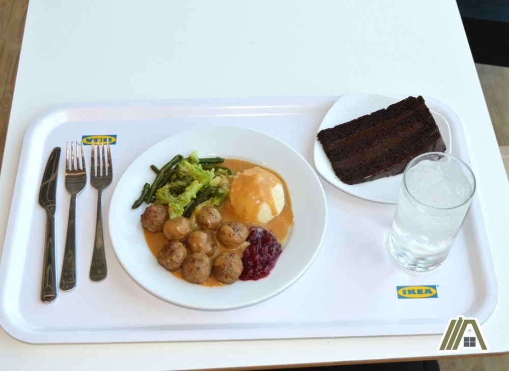 Swedish food at IKEA food store, plate with meatballs, mashed potato and veggies with a plate of chocolate cake and a glass of water