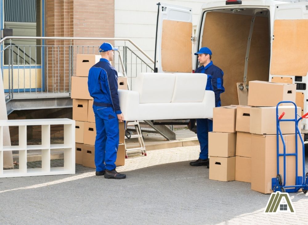 Men in blue uniform carrying a two seater white sofa for delivery