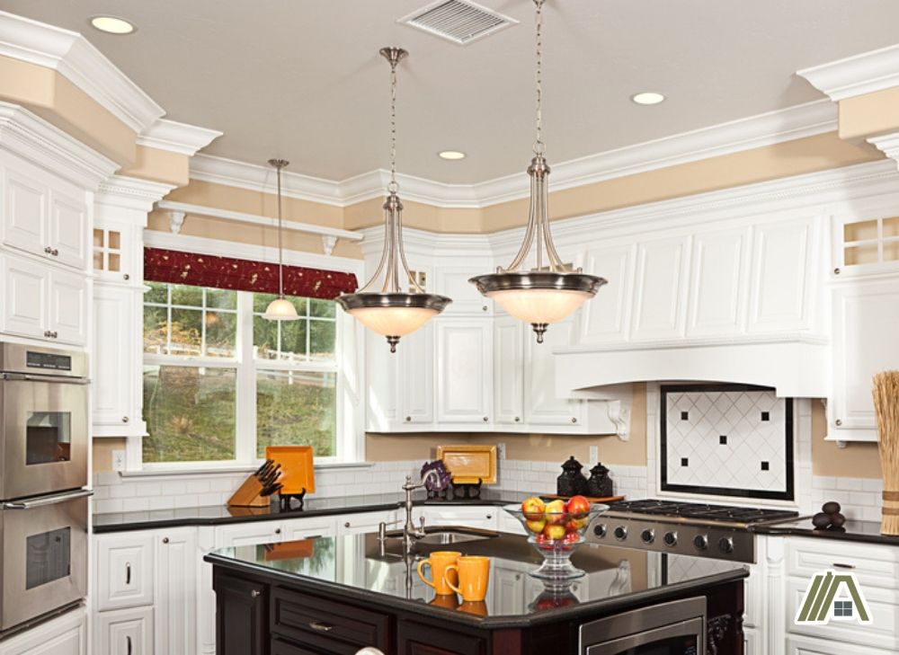Old style kitchen with 2 pendant lights on the top of the island, make up air and stove exhaust