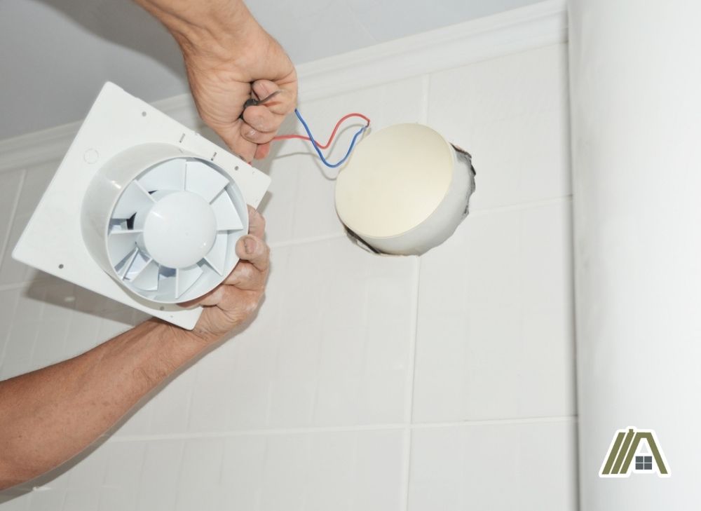 Electrician removing and repairing the bathroom fan