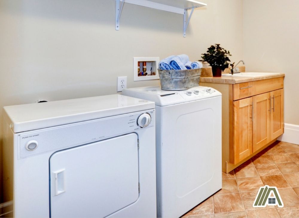 Gas dryer and washer inside the laundry room with a faucet