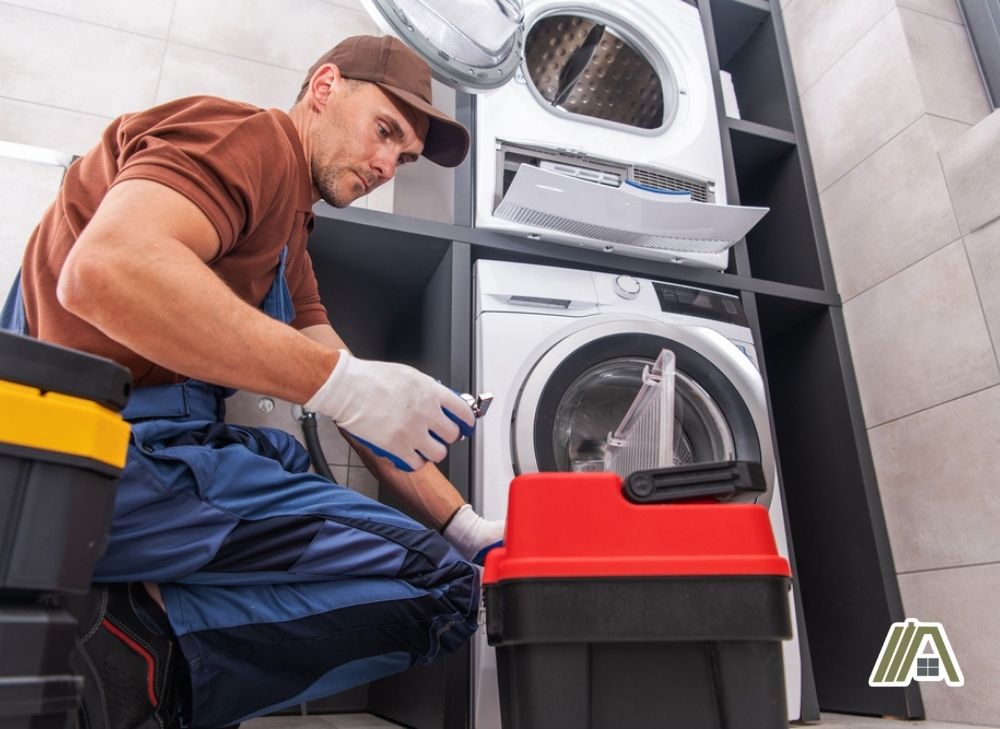 Man repairing a washer and a dryer inside the laundry room