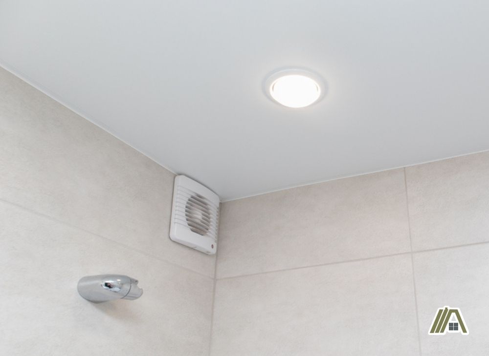White bathroom fan installed in the upper corner of the bathroom