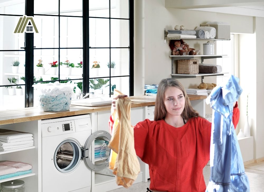 Woman holding two clothes inside the white laundry room
