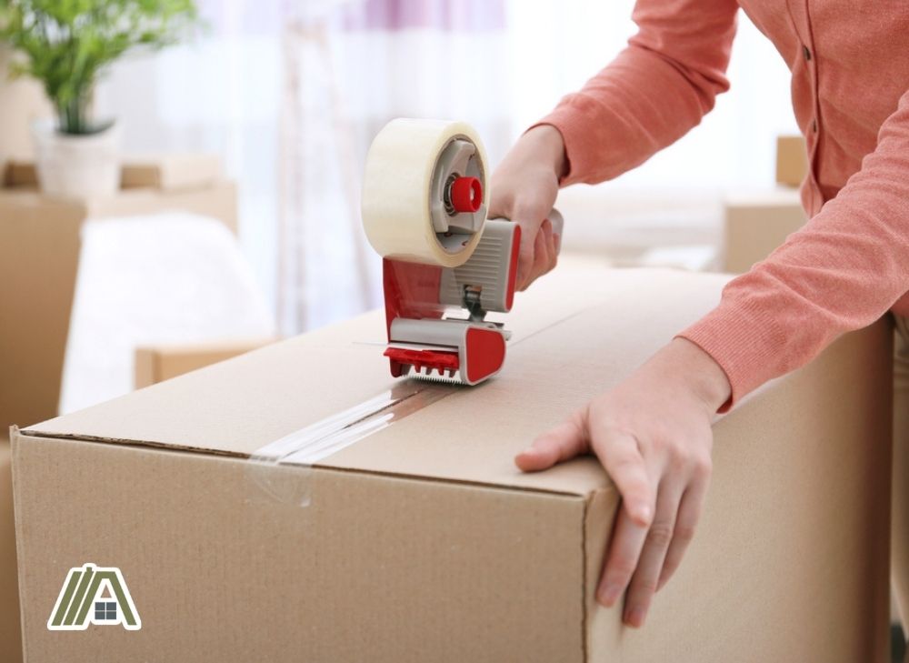 Woman placing a packing tape on a box using a tape dispenser