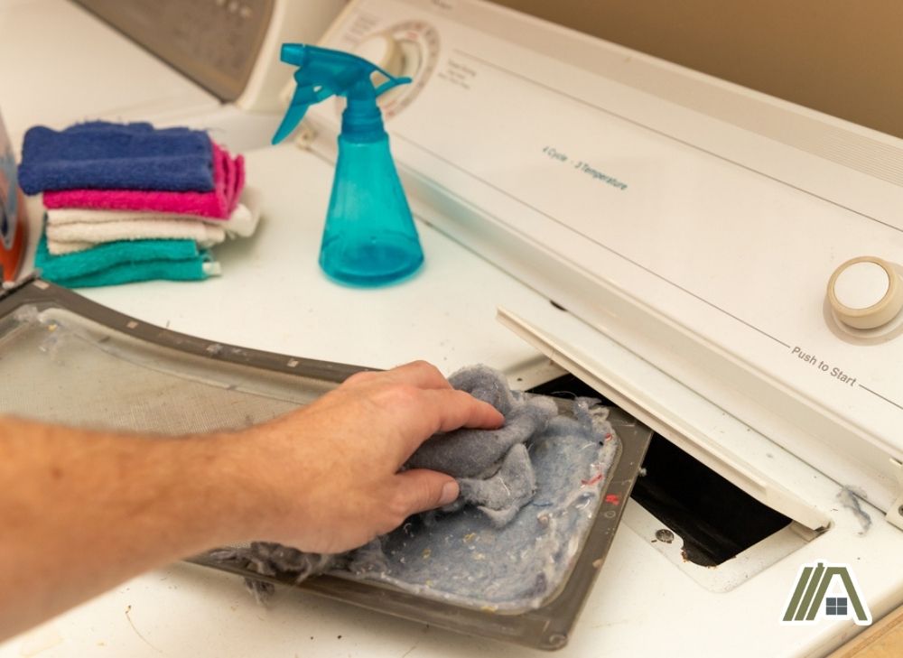 Man removing lint from the lint trap of a gas dryer